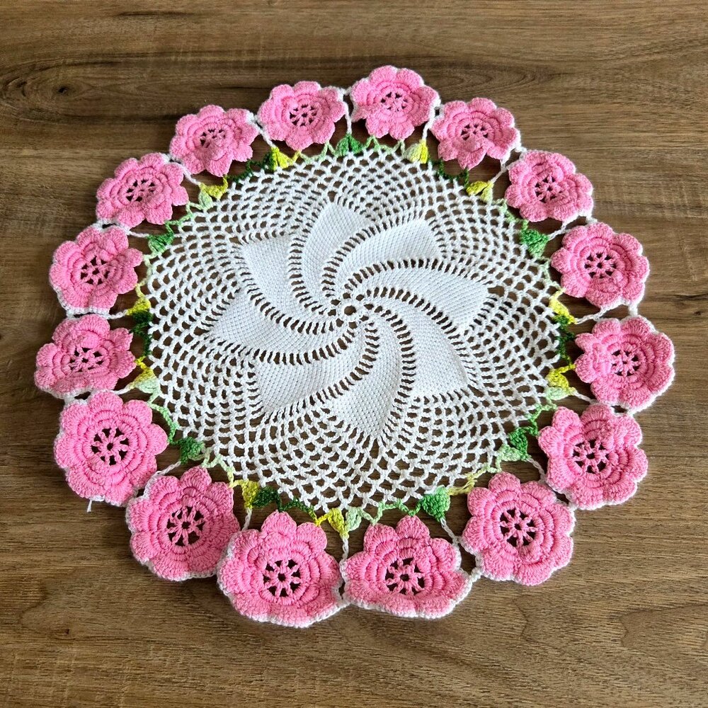 Hand made crochet doily with pink flowers.